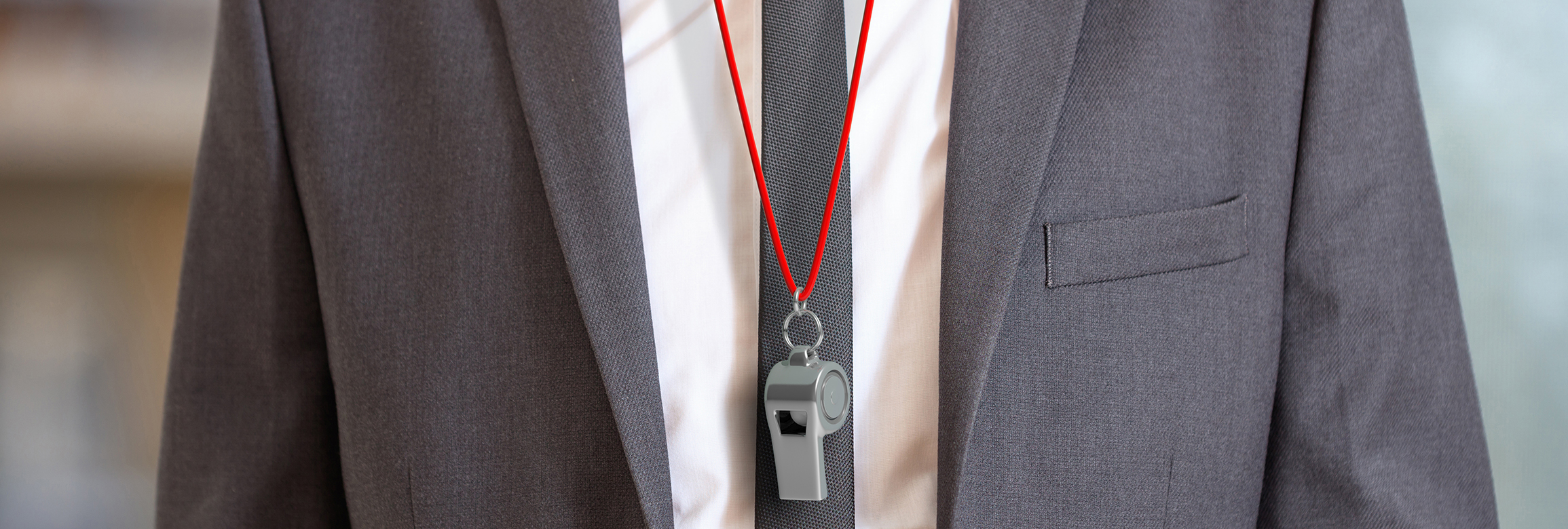 A close up of a man wearing a suit. He is a career coach and there is a whistle with a red lanyard around his neck.