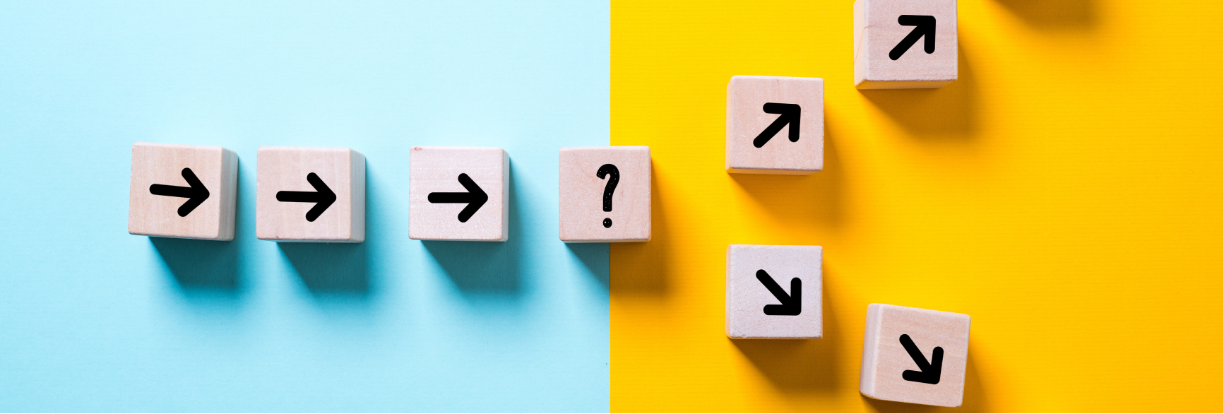 A photo of arrows and question marks on blocks. Three arrows on the left point to a question mark on the right. The arrows diverge into two paths: one angling 45 degrees north - the other angled 45 degrees south. The image represents one path that diverges into two different paths, with a choice of path that can be taken.