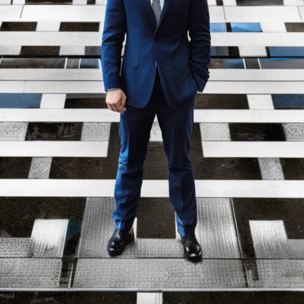Man in business suit with oen hand in pocket and the otherclenched fist