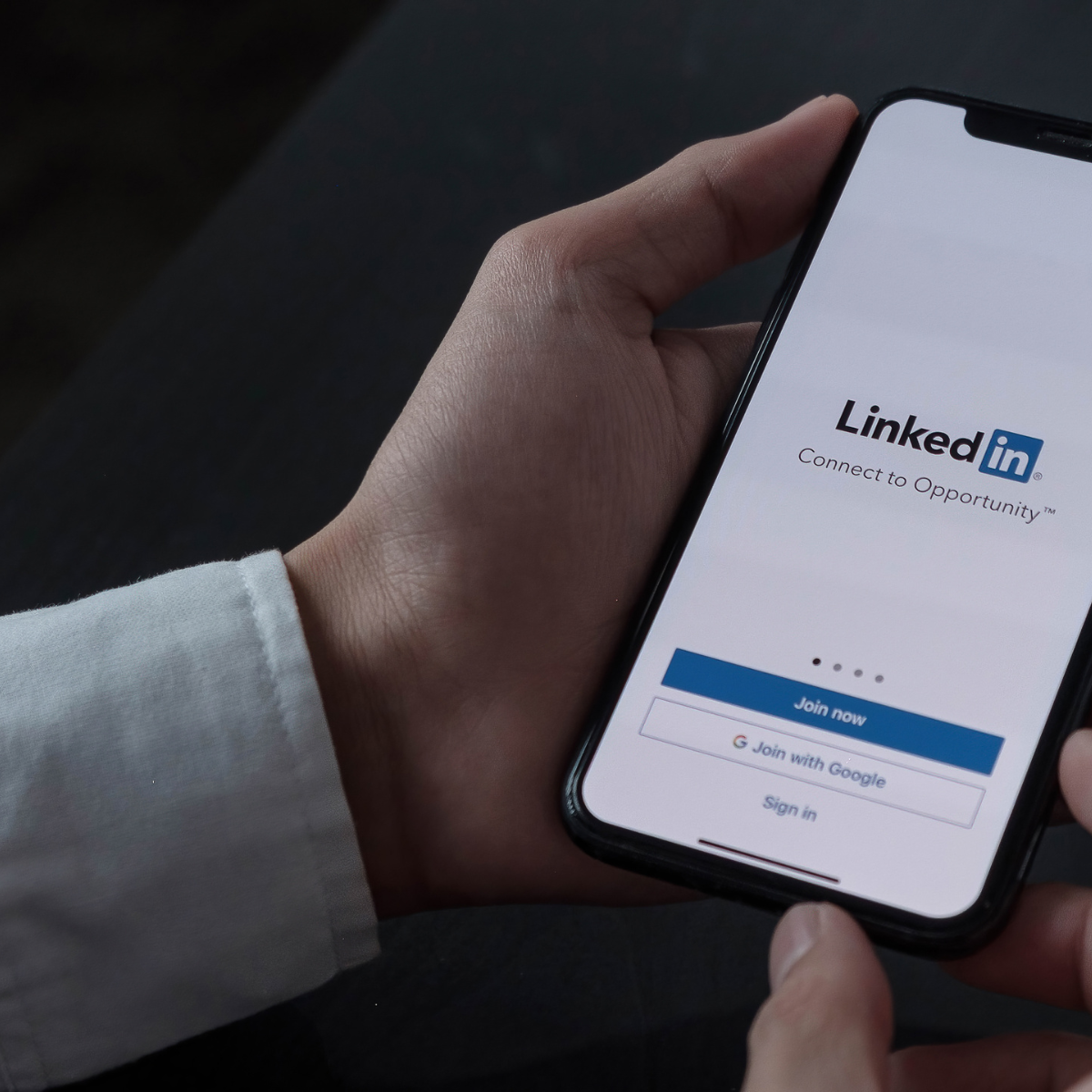 Man holding mobile phone displaying LinkedIN login screen