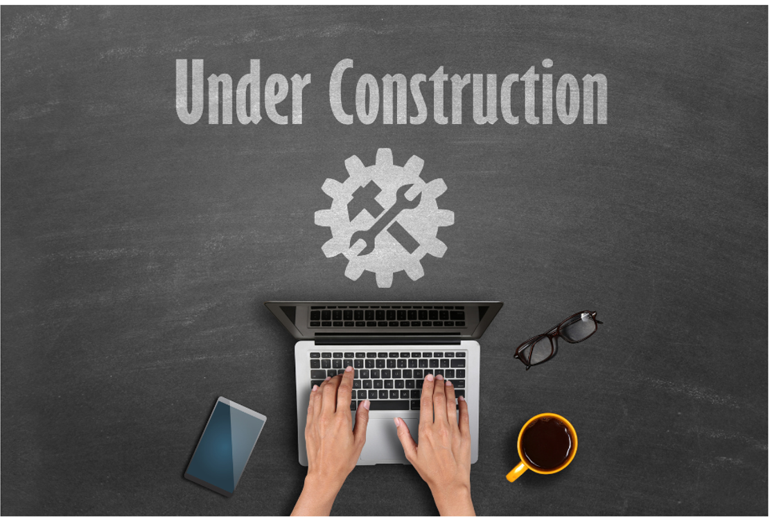 Sign Under Construction and man's hands on a keyboard